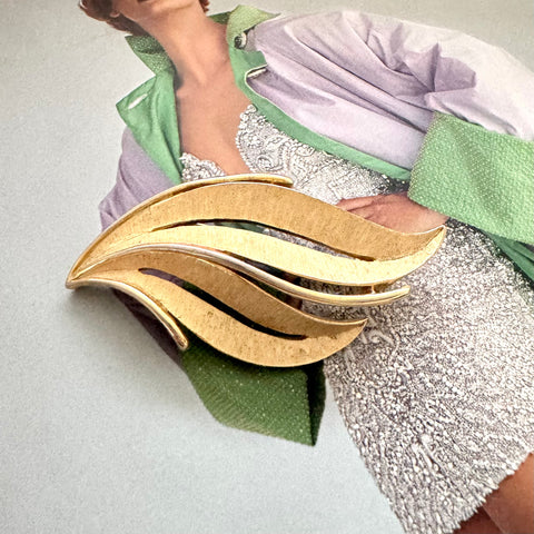 Mid century Crown trifari gold tone leaf brooch photographed on an image of Linda Evangelista in a Vogue magazine cover