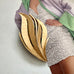 Mid century Crown trifari gold tone leaf brooch photographed on an image of Linda Evangelista in a Vogue magazine cover