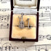 Silver guitar and saxophone charms in a jewelry box on sheet music