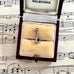 Silver saxophone charm in a jewelry box on sheet music