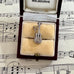 Silver guitar-shaped charm in a jewelry box on sheet music
