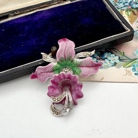 Floral brooch with pink and green leaves on a white surface