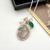 Necklace with a vintage Saint Anne pendant and green stone on a white surface