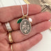 Necklace with a vintage Saint Anne pendant held in a hand, showing details of the jewelry.