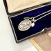 Necklace with a vintage Saint Anne pendant and green stone in an open jewelry box on a white background