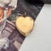 Gold heart-shaped locket with 'Rolled Gold' engraving on a textured surface.