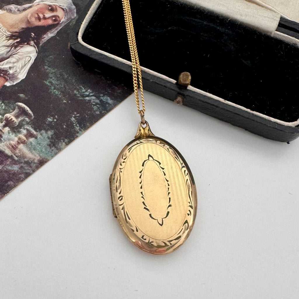 Vintage rolled gold locket on a chain with an open jewelry box in the background