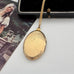 Gold locket on a white surface with a vintage-style card in the background