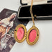 Vintage gold locket with pink interior on a white surface with an open box in the background.