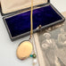 Gold locket with pendant on a chain next to an open jewelry box and vintage photograph.