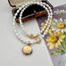 Vintage rolled gold locket and pearl necklace on a vintage postcard and jewellery box