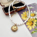 Vintage rolled gold locket and pearl necklace on a vintage postcard and jewellery box