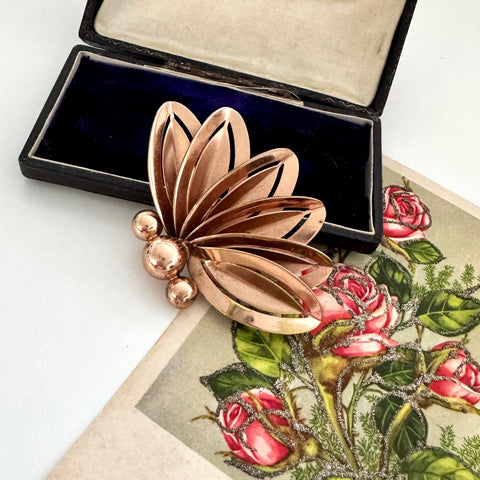 Rose gold floral brooch on a vintage-style card with roses and leaves.