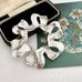 Vintage 1971 silver tone Sarah Coventry ribbonette brooch on an old postcard and with a box