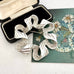 Vintage 1971 silver tone Sarah Coventry ribbonette brooch on an old postcard and with a box