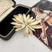 Vintage signed Sarah Coventry brooch from 1965 Tropics Collection on a textured surface with an open jewelry box and vintage illustration.