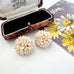 A pair of signed Grosse pearl cluster earrings displayed in front of an open vintage jewelry box, with a floral card partially visible on the right.