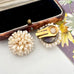 A pair of vintage Grosse cluster earrings with cream pearls and gold-tone metal, displayed next to an open vintage jewelry box on a light surface.