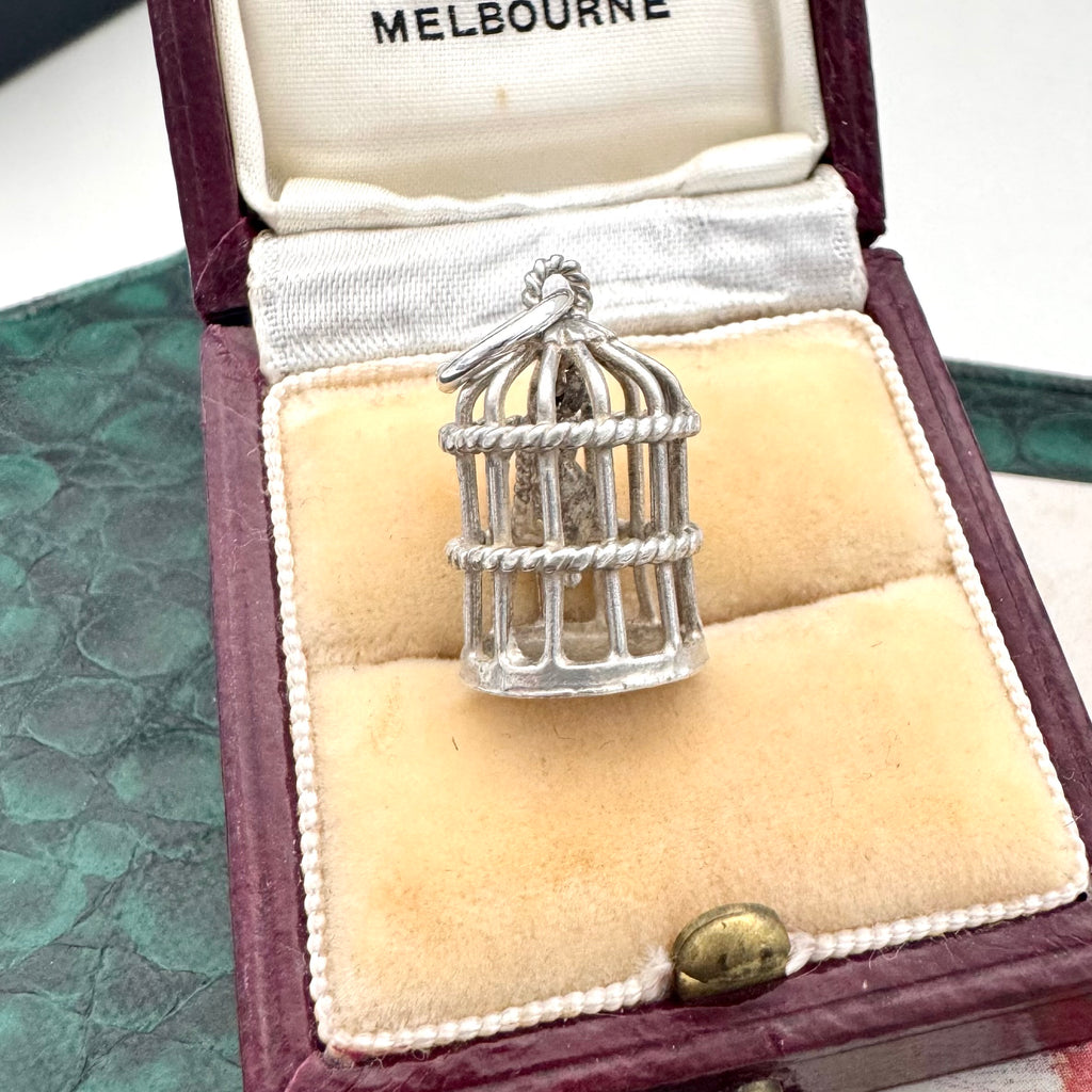 Silver birdcage pendant charm in an open jewelry box with 'Melbourne' branding.