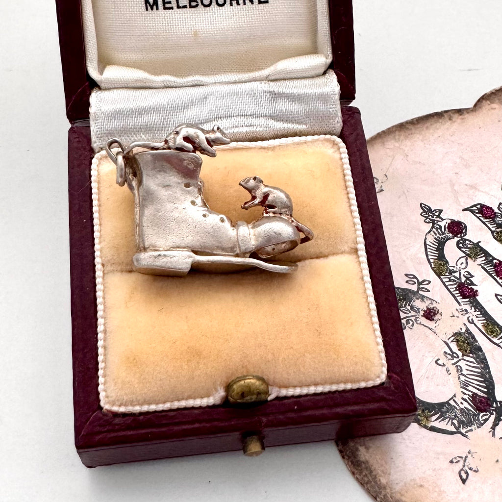 Vintage silver boot and mice charm on a jewellery box and with an old postcard in the background