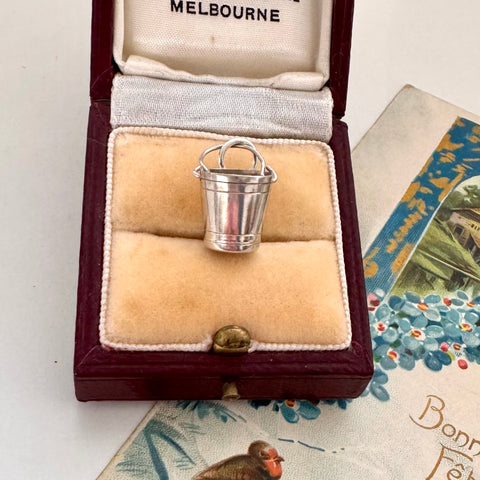 Vintage silver bucket charm in a jewelry box with 'Melbourne' branding.