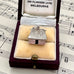 Vintage silver Fijian bure house-shaped pendant in a jewelry box on sheet music