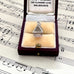 Vintage silver Fijian bure house-shaped pendant in a jewelry box on sheet music