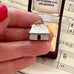Small silver house charm held between fingers on sheet music