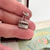Vintage silver cable car charm held between fingers with a decorative fan in the background