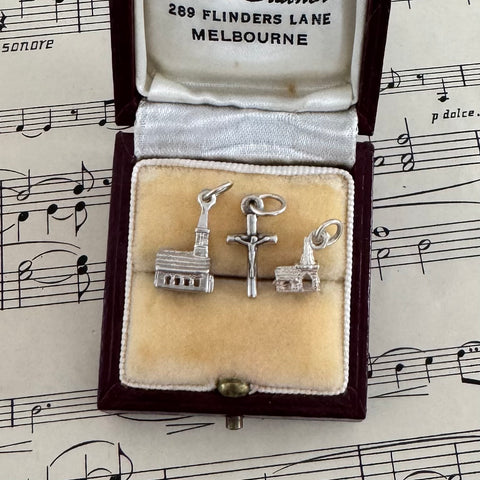 Three silver charms in a jewelry box with sheet music in the background