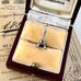 Silver Eiffel Tower charm in an open jewelry box with vintage newspaper background