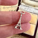 Silver Eiffel Tower charm held between fingers with vintage photo album in background