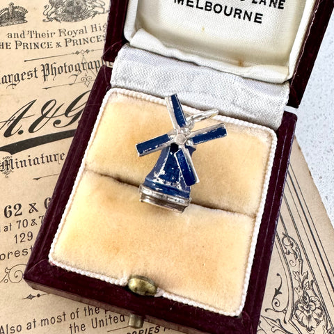 Blue and silver windmill charm in a jewelry box on an old newspaper background