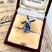 Blue and silver windmill charm in a jewelry box on an old newspaper background