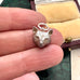 Silver fox charm held between fingers with a jewelry box in the background