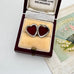Heart-shaped open locket in a vintage box with a fan and card in the background