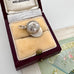 Vintage silver jockey cap charm/pendant in a jewelry box on a textured surface