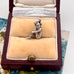 Silver pixie charm in a jewelry box with a floral patterned surface.