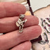Vintage silver Mexican guitar player charm in a womans hand with a decorative background