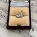 Silver vintage old boot charm in a jewellery box on sheet music background