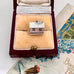 Silver house charm in a jewelry box on a decorative surface with a bird figurine.