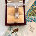 Vintage silver opening house charm in a jewelry box with a decorative card in the background