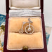 Silver bicycle charm in a jewelry box with a floral patterned fabric background