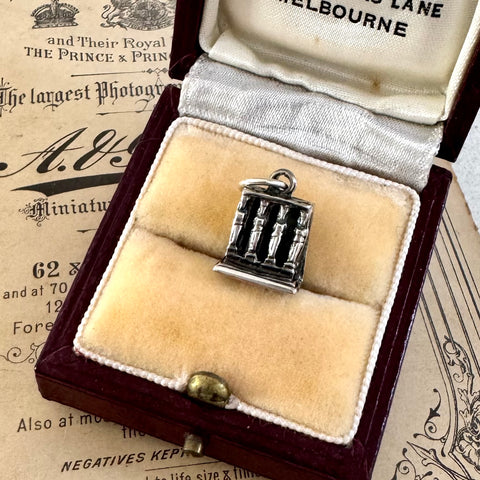 Vintage silver charm of the porch of maidens at the The Acropolis in a decorative box on an old newspaper background