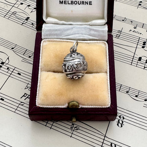 Vintage silver decorative ball charm in a jewelry box on sheet music