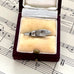 Vintage silver shoe charm in a jewelry box on sheet music