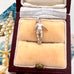 Silver soccer player charm on a beige cushion in an open jewelry box with a decorative background.