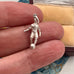 Silver soccer player charm held between fingers with a patterned fabric background