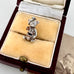 Silver teddy bear charm in a jewelry box with a vintage photo in the background