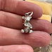 Vintage silver bear charm held between fingers against a neutral background